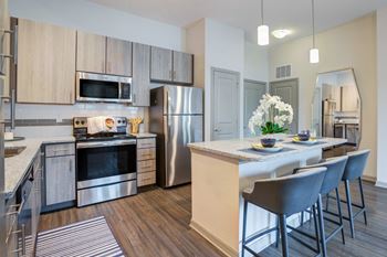an open kitchen and dining area with stainless steel appliances and a table with chairs at Century Town Center, Gainesville